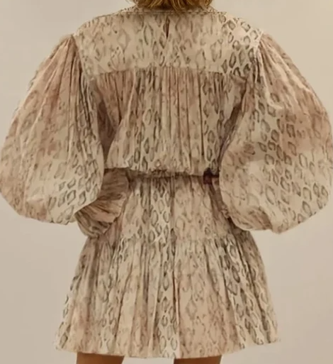 Close up of model wearing the Aje mini dress in serpentes, showing the puff sleeves and lightweight fabric.