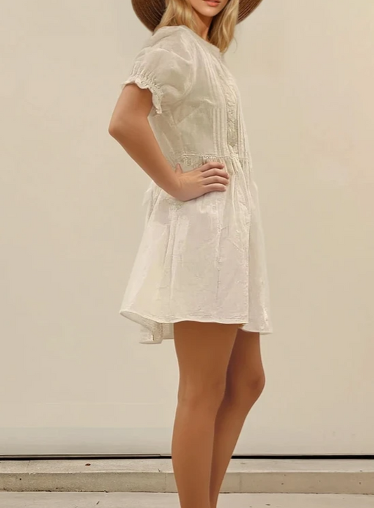 Model in profile pose wearing the Auguste the Label Mara Mini Dress, with hands on hips and a subtle swing in the skirt.