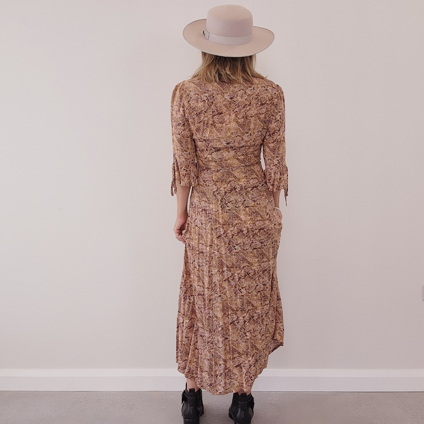 Model showing back view of the Auguste the Label Pia wrap dress in snake print, showing the tie details on sleeves.