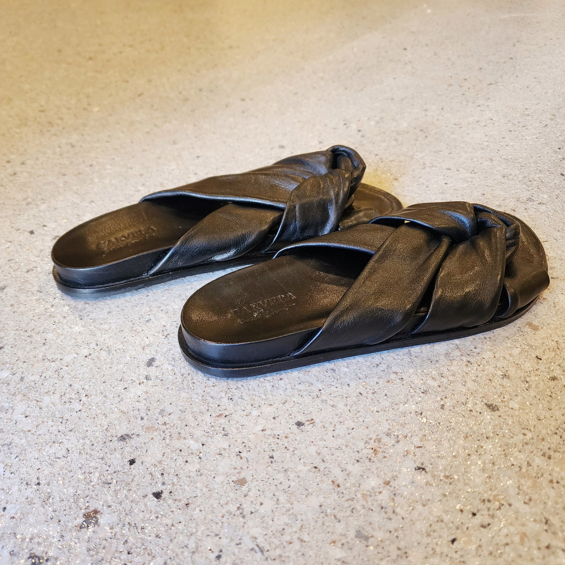 Carvela knot leather slides in soft black, side angle showcasing twisted strap design and padded insole