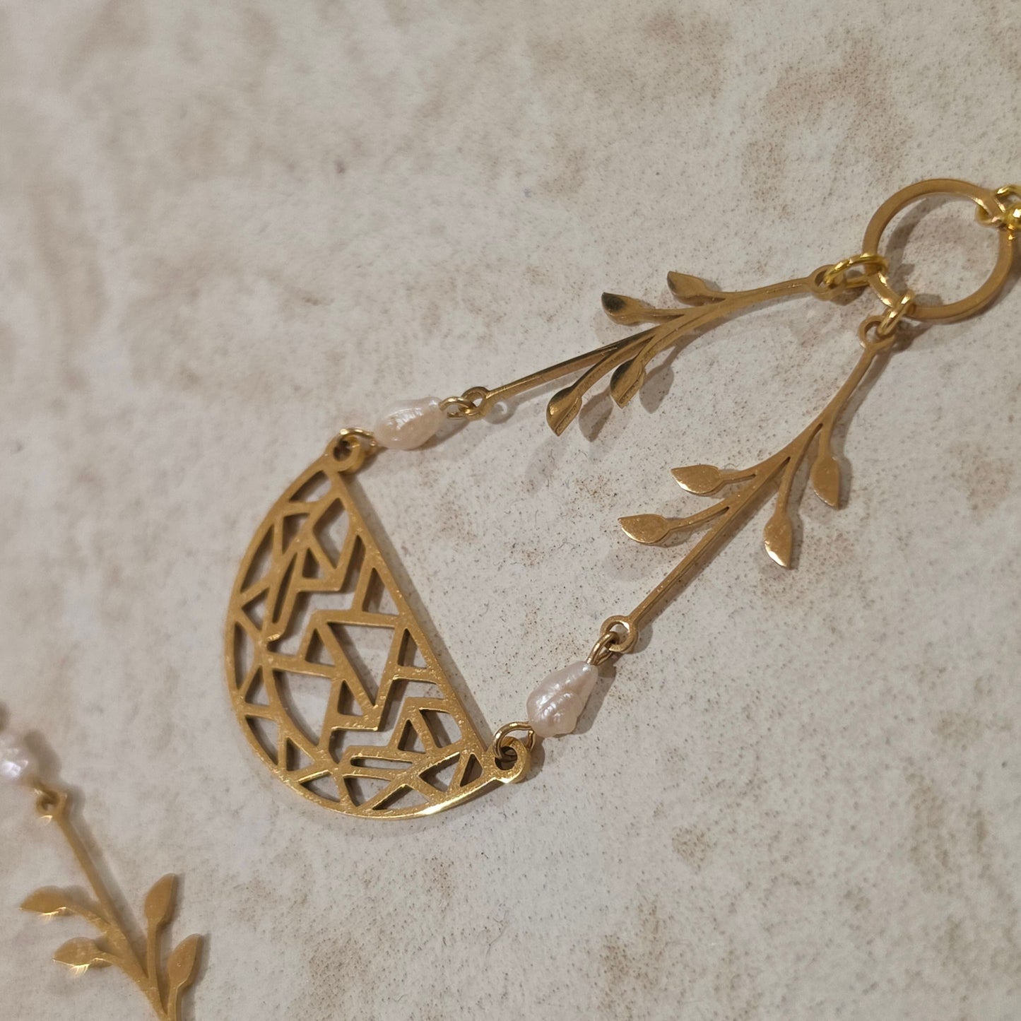 Close-up view of the Coral handmade pearl earrings, showing the unique shape and irregularities of the natural pearls reworked with gold plated stainless steel components.