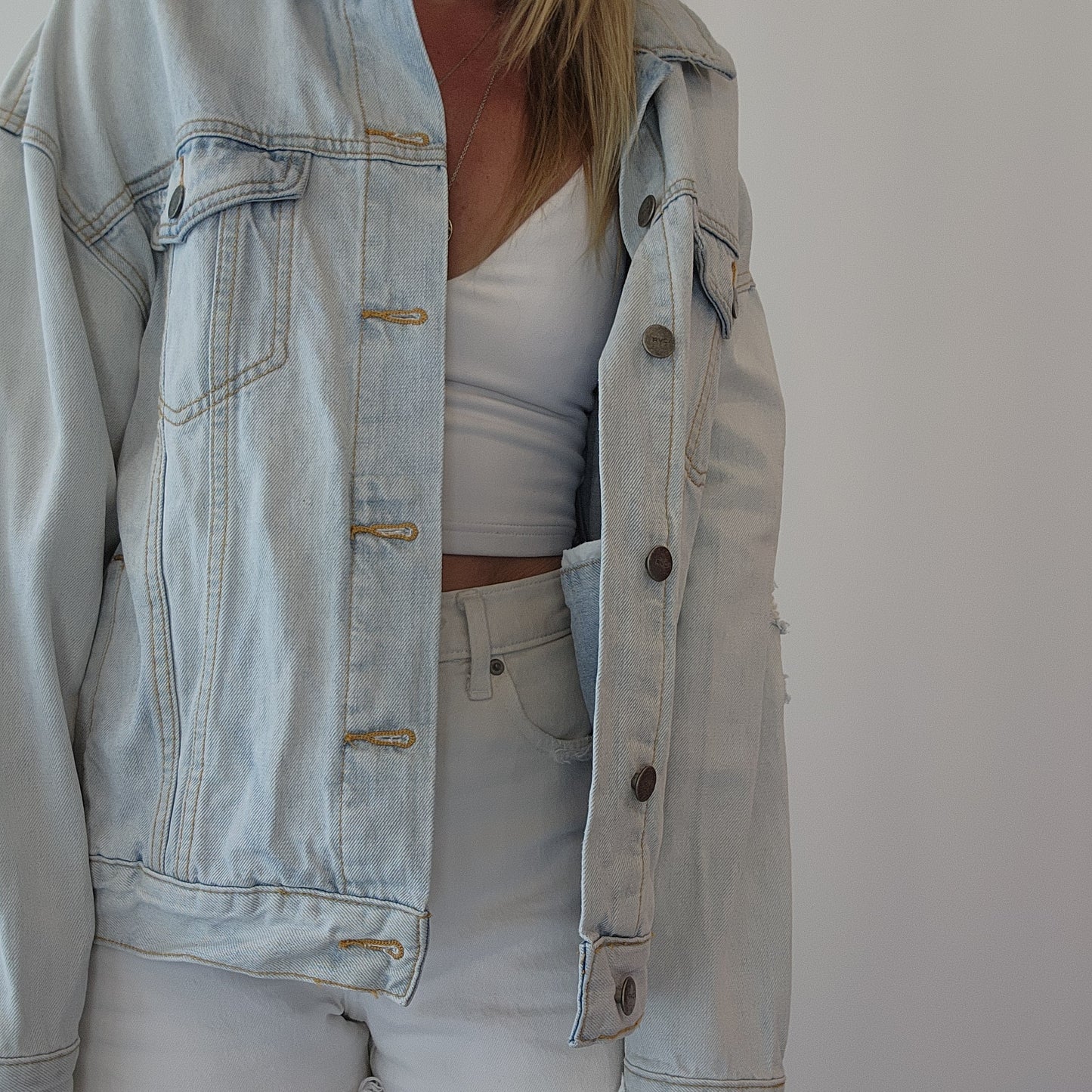 Model wearing a light wash denim button up jacket by clothing designer RVCA
