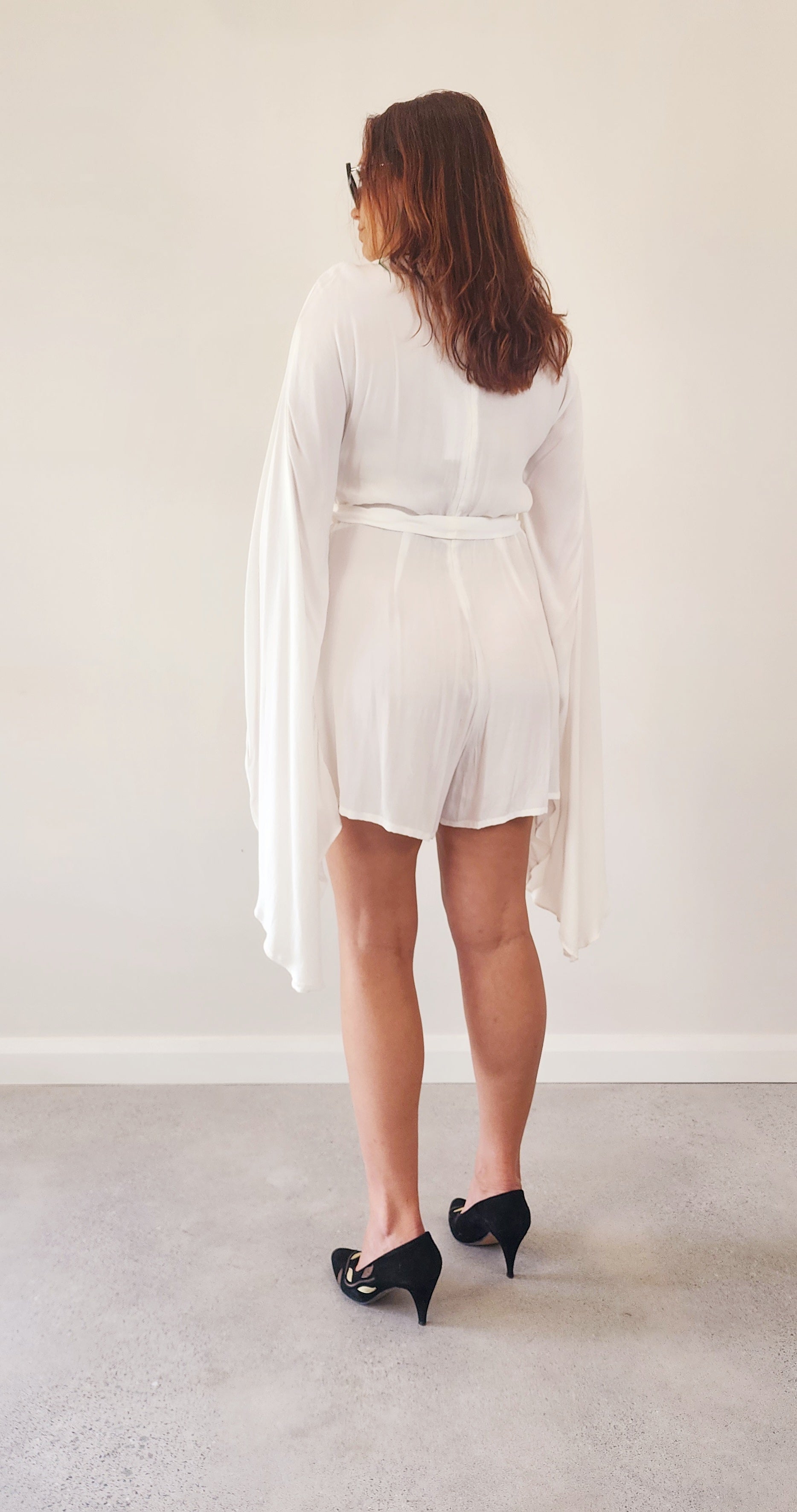 Brand new Incyda white jumpsuit with a tie belt. Cape style playsuit with long flared sleeves in a size 12. Available online at Wilson Avenue