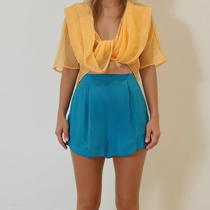 Alternate front angle of the Johansen top styled with vibrant blue Zimmermann silk shorts, tied loosely.