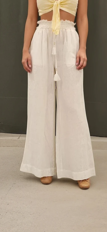 Model showing the front view of the Kivari wide leg linen pants, showing the gathered waist and drawstring with tassel ends.