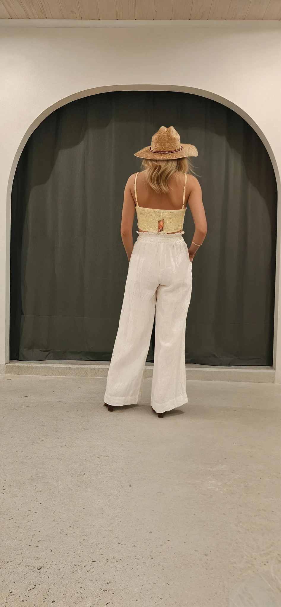 Model showing the back view of the Kivari linen pants, showing the minimalist style and wide leg.