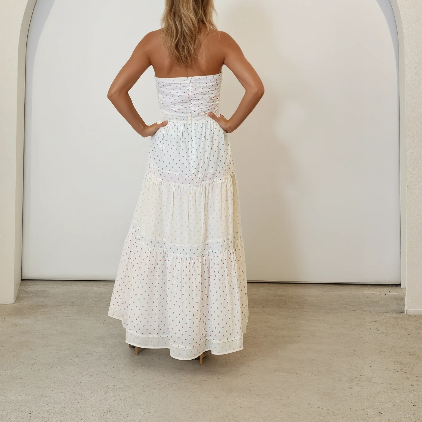 Model wearing the Marlo Yazmin dress, showing the back view with zip up the middle, ruched back and tiered flare skirt.