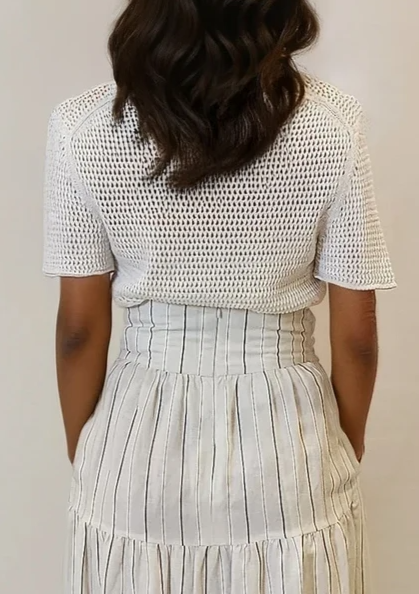 Rear view of the top highlighting its textured knit and clean silhouette, tucked into a high-waisted skirt.