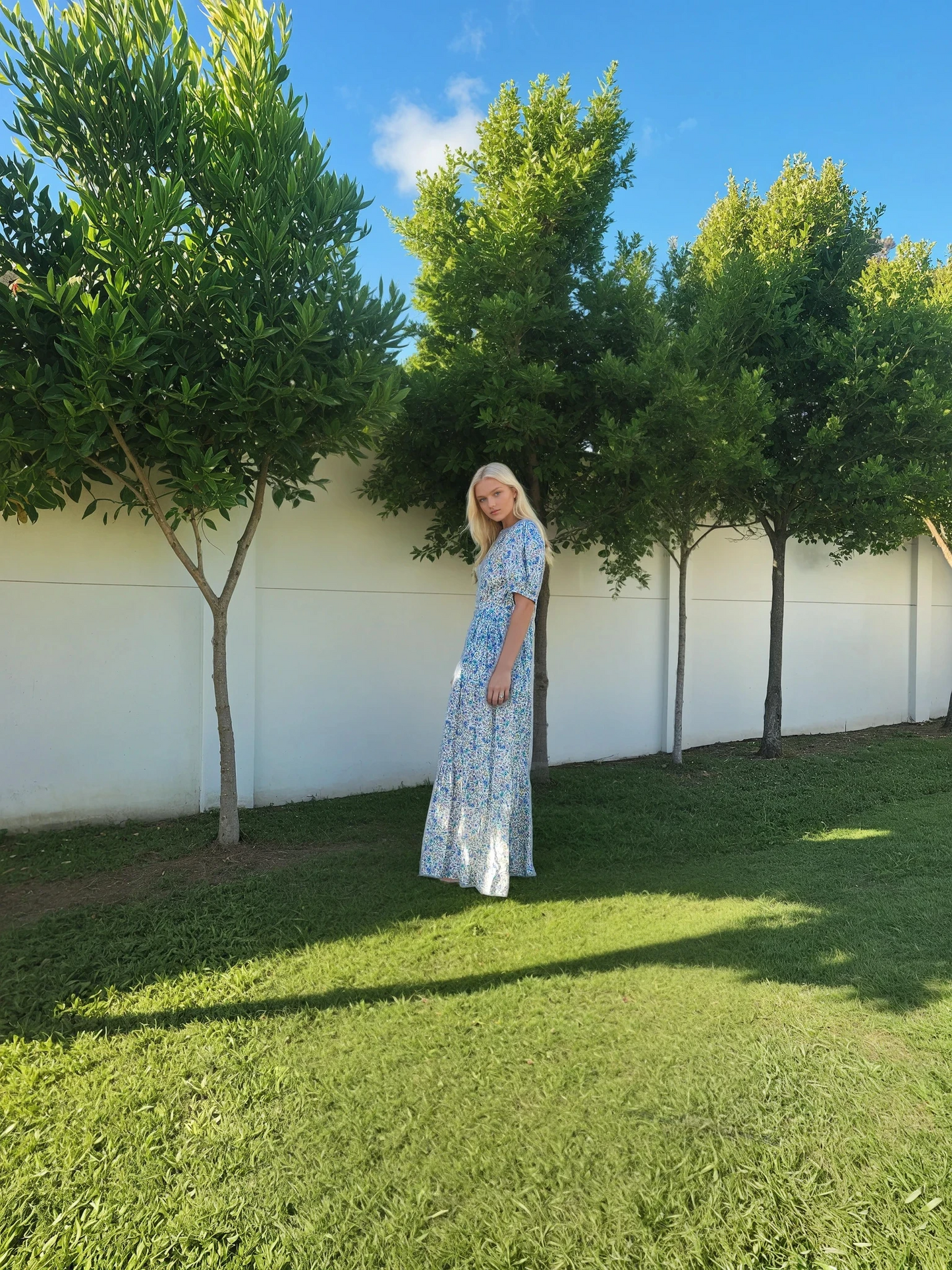 Model showing the side view of the Oak Meadow blue floral maxi dress in size small.