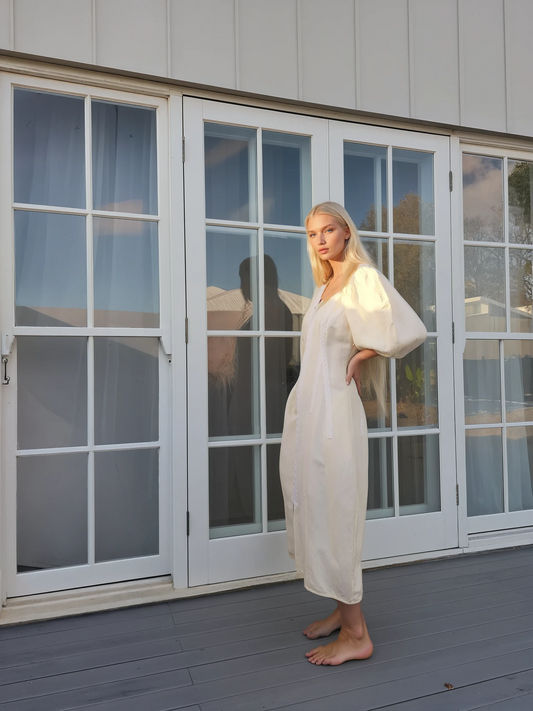 Model wearing the sculptured Oroton dress in light lemon, showing the side view of the puff sleeves.