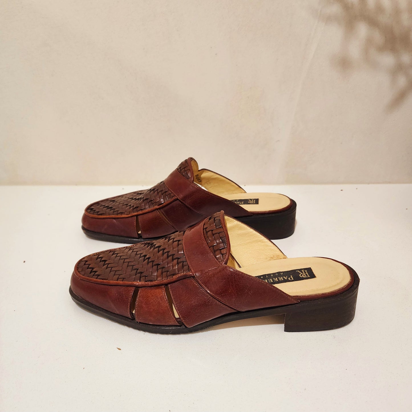 Side view of the Parker Roche leather mules, showing the woven detail and side panels.
