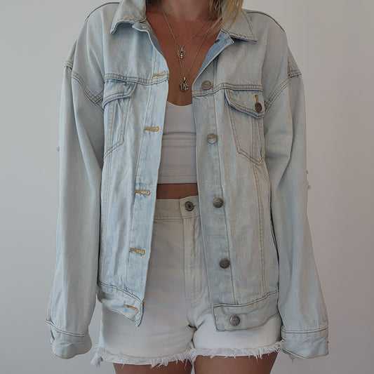 Front view of RVCA denim jacket styled with shorts and a crop top, showing classic button-up design and relaxed fit. Size S