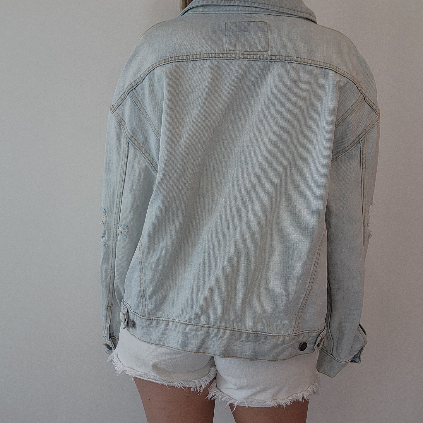 Back view of RVCA denim jacket, highlighting structured cut and adjustable tabs, styled casually for a layered look