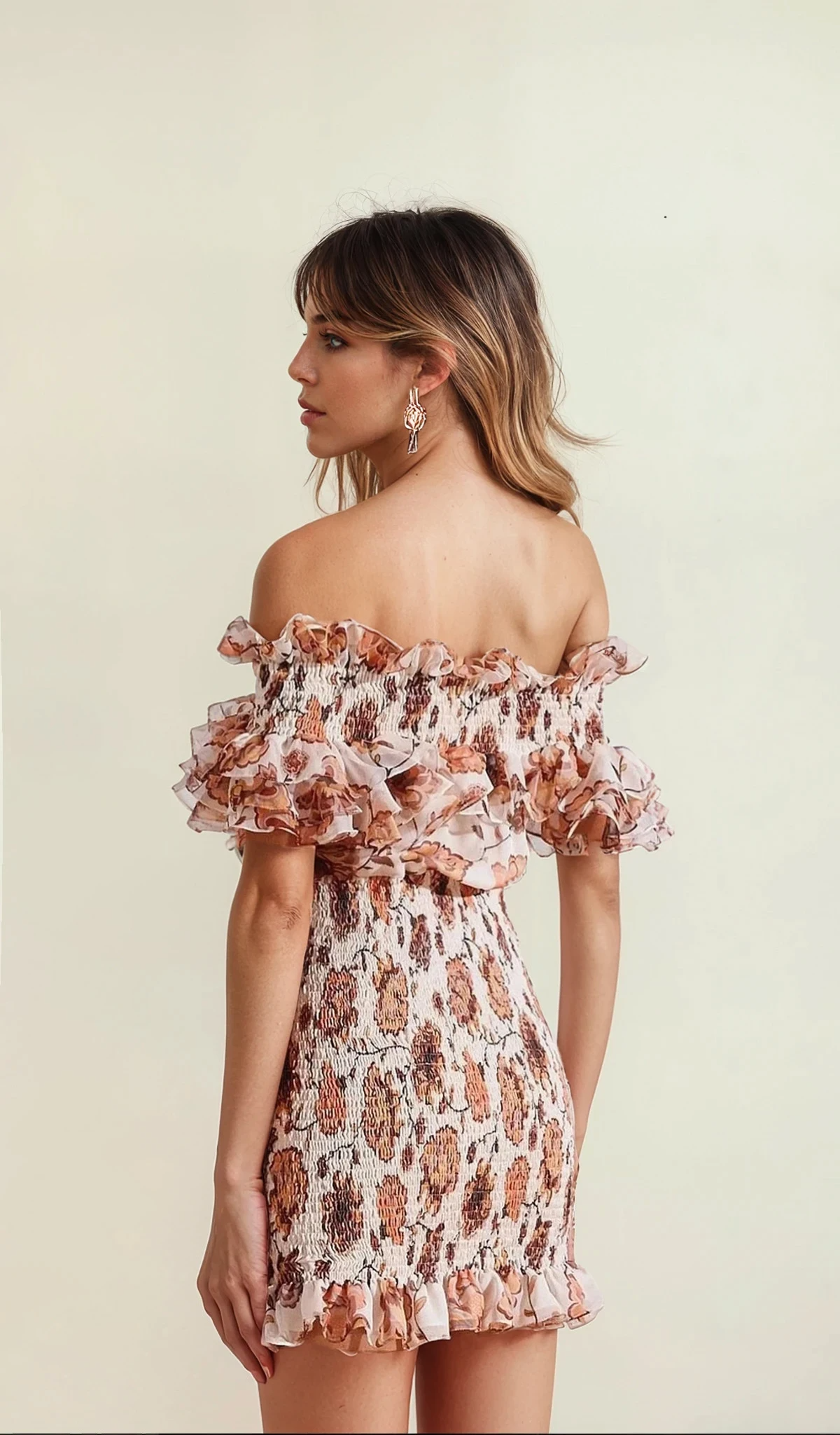 Model showing the side view of the floral Shona Joy Baez mini dress in earthy florals, with frill neckline, hemline and sleeves.
