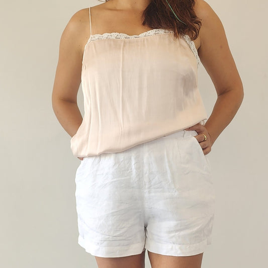 Model wearing the St Agni white linen shorts, showing the high waist design and pockets.