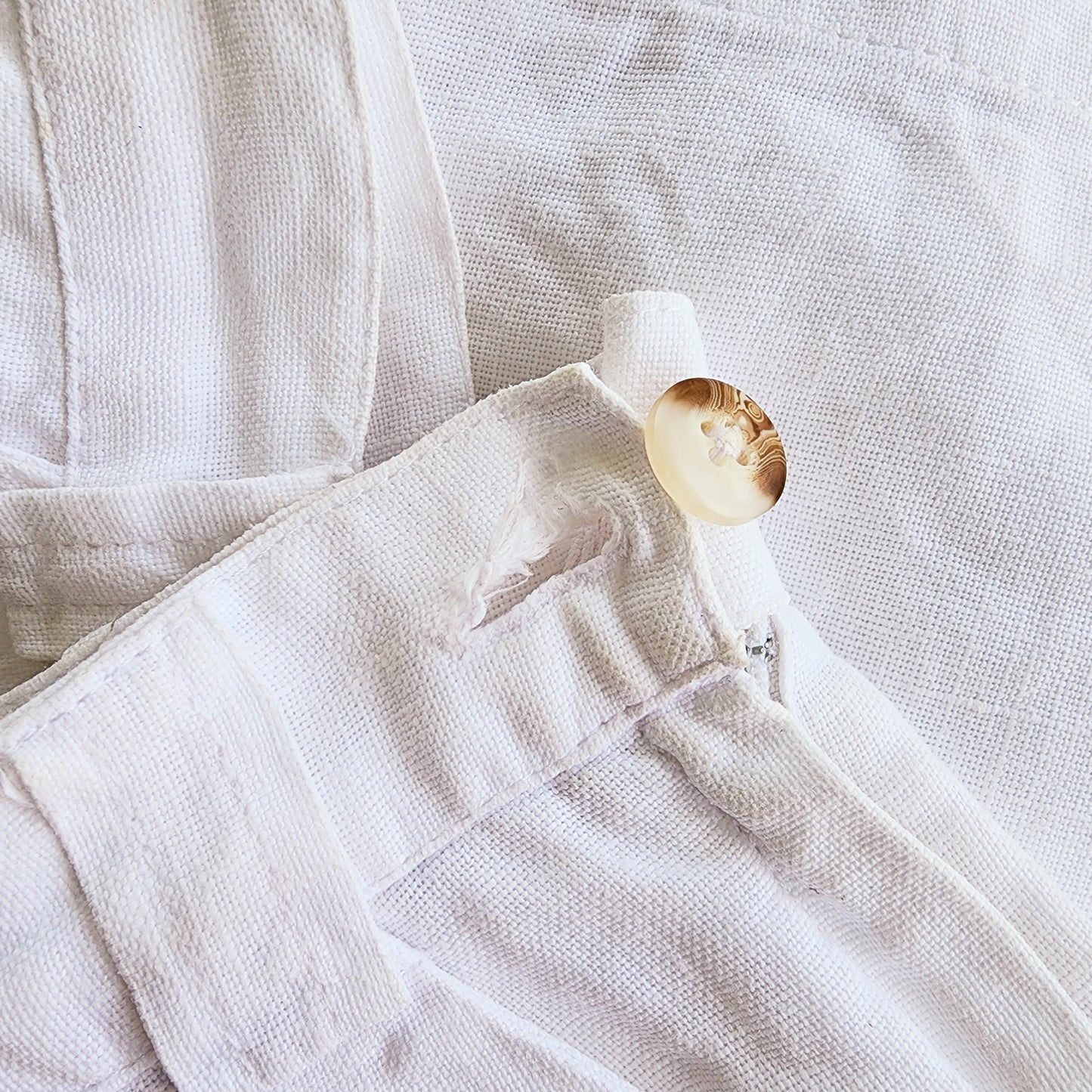 close up image of the St Agni shorts button hole, where there is some fraying of the fabric.