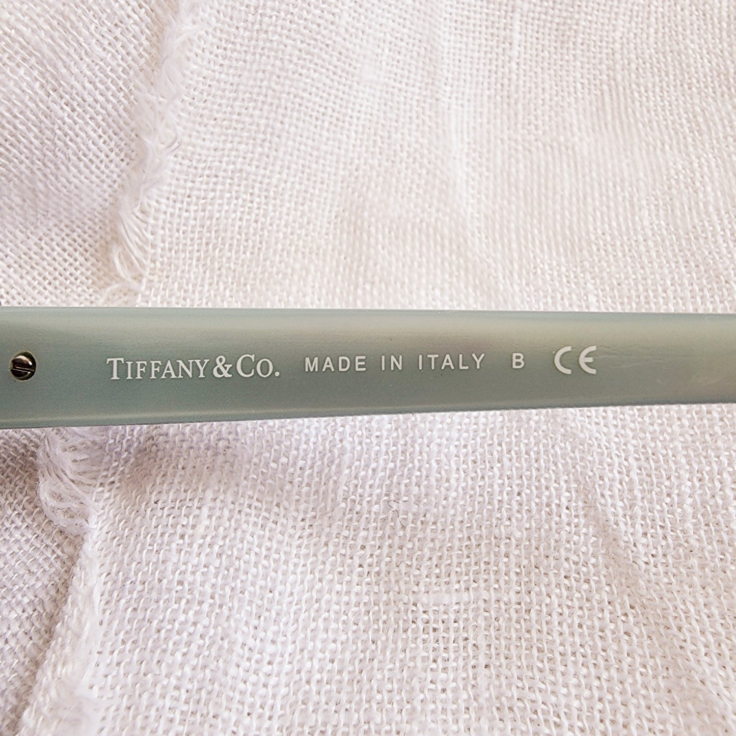 Close up of the left temple on the Tiffany & Co sunglasses, showing brand name and made in Italy stamp.