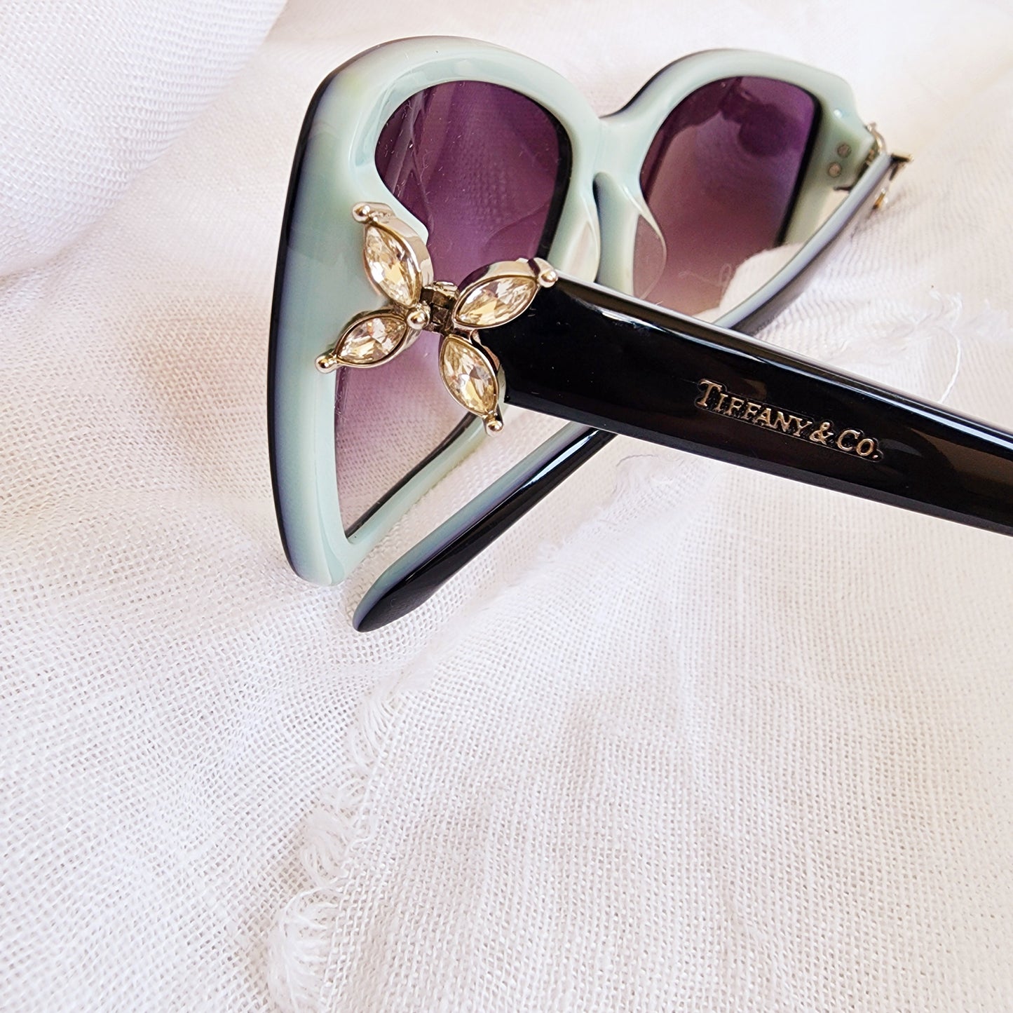 Close up of Authentic Tiffany & Co. sunglasses showing Swarovski Crystal side flower detail and brand name on temple.
