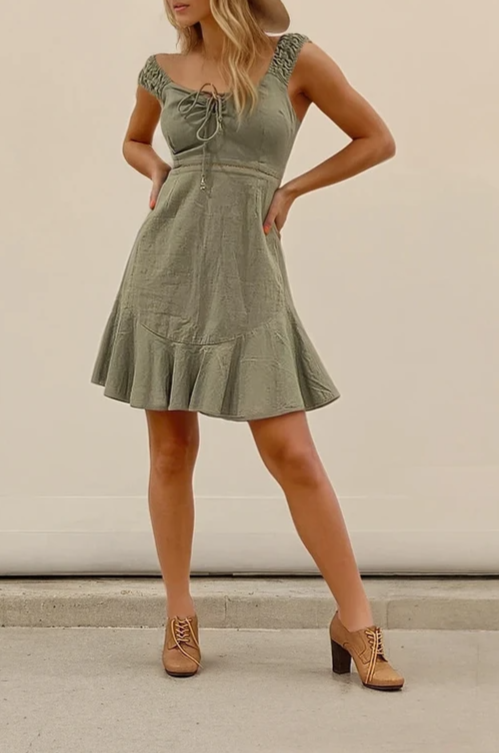 Model standing confidently in the Tigerlily Sollemita Dress, hands on hips, wide-brim hat completing the look.