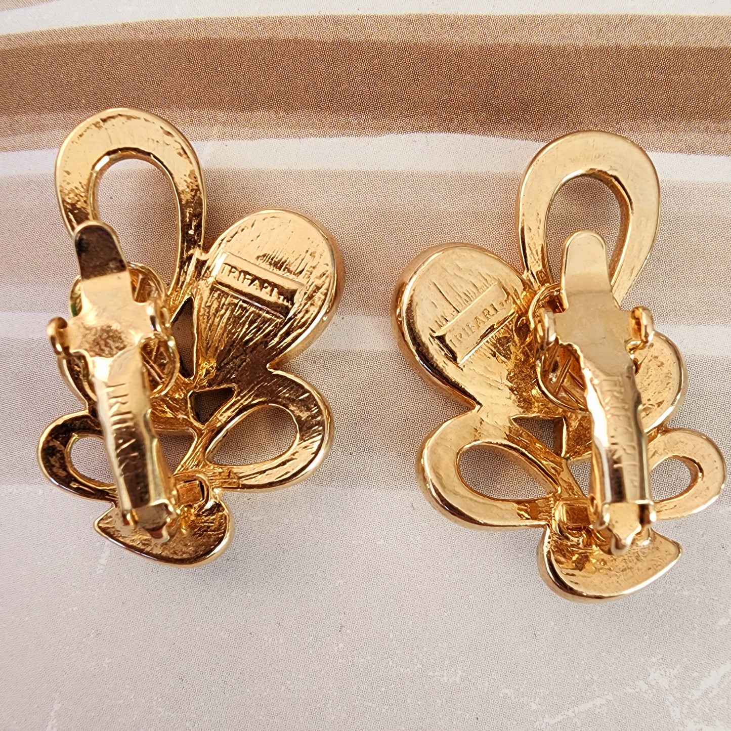 Back view of the vintage Trifari clip-on earrings, showing the gold tone and designer brand stamps.