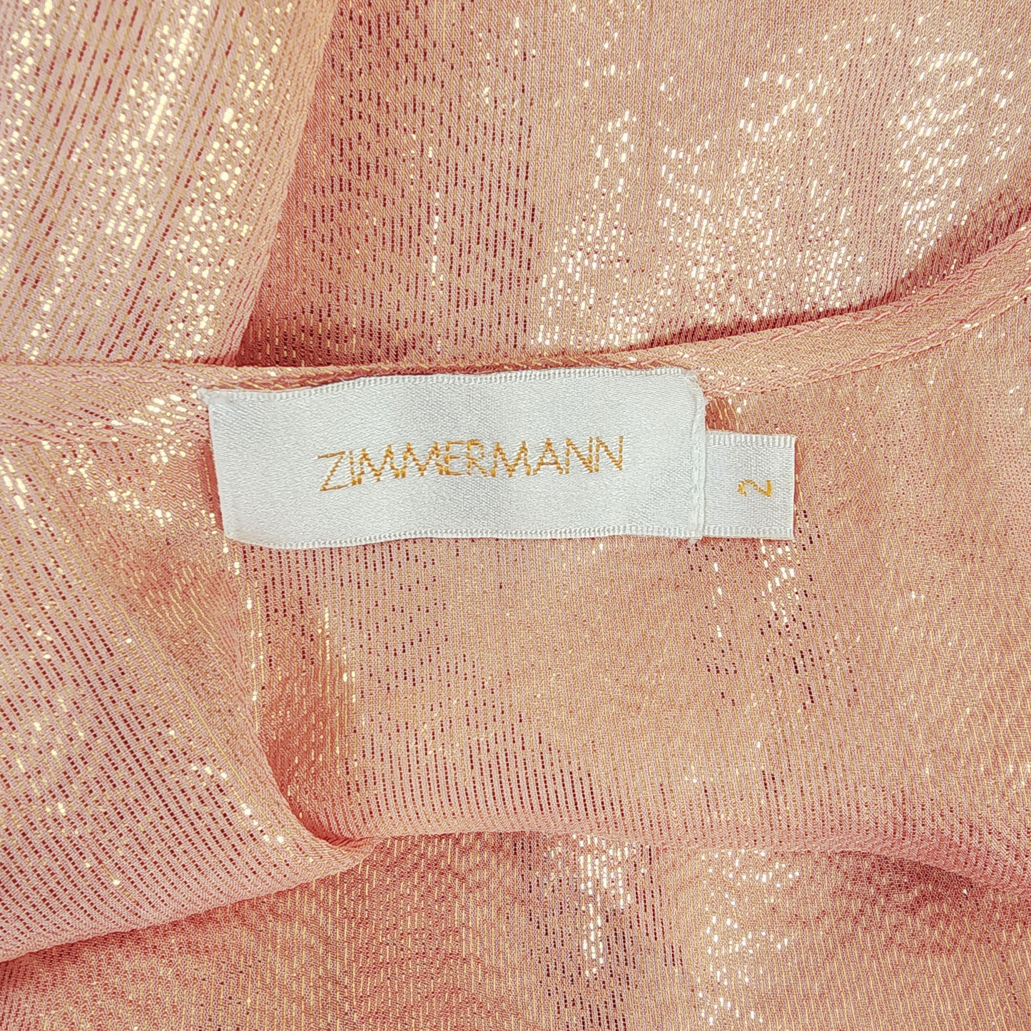 Close up view of the Zimmermann singlet blouse, showing the shimmering fabric and brand tag.