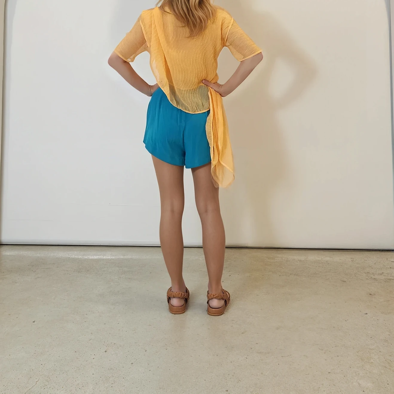 Rear view of the blue Zimmermann shorts paired with a sheer orange Johansen top, showing clean lines and relaxed fit.