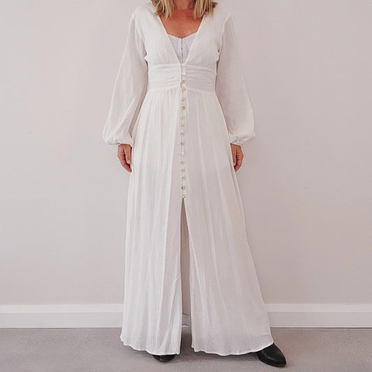 White maxi dress with V neckline, long sleeves and button front, worn closed