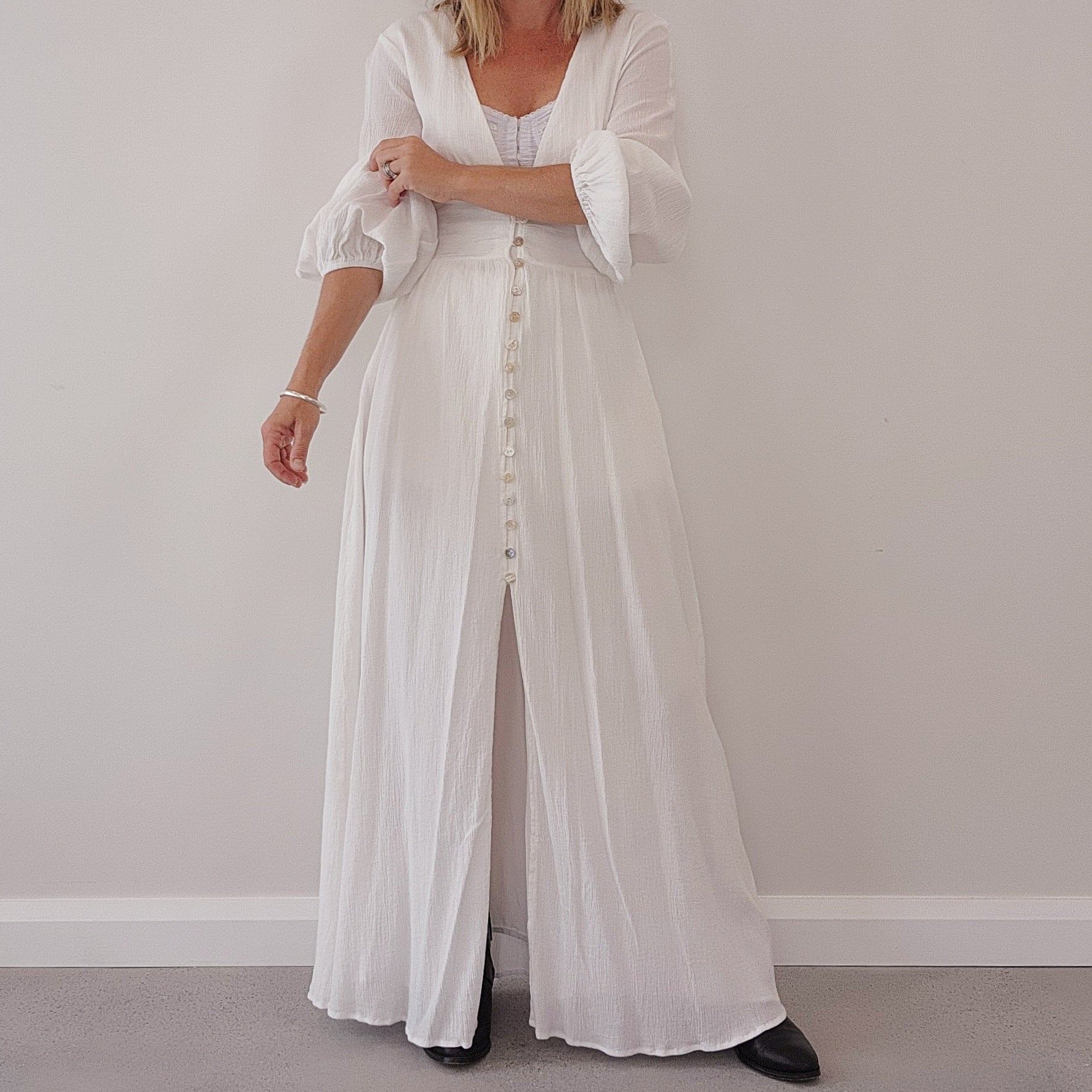 Close-up of white maxi dress showing sleeve volume, wide band waist and pearly buttons