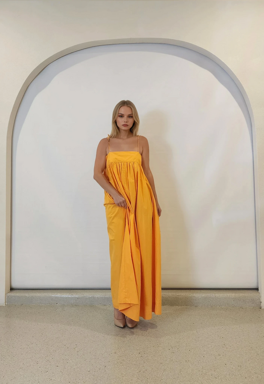 Model wearing the Daisy Says marigold midi dress front-on, showing the bold colour and free flowing style.