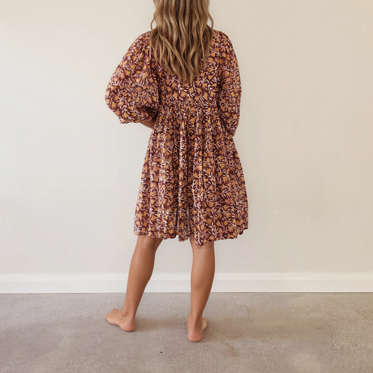 Back view of woman wearing the long-sleeved Daughters of India Kyra floral mini dress.
