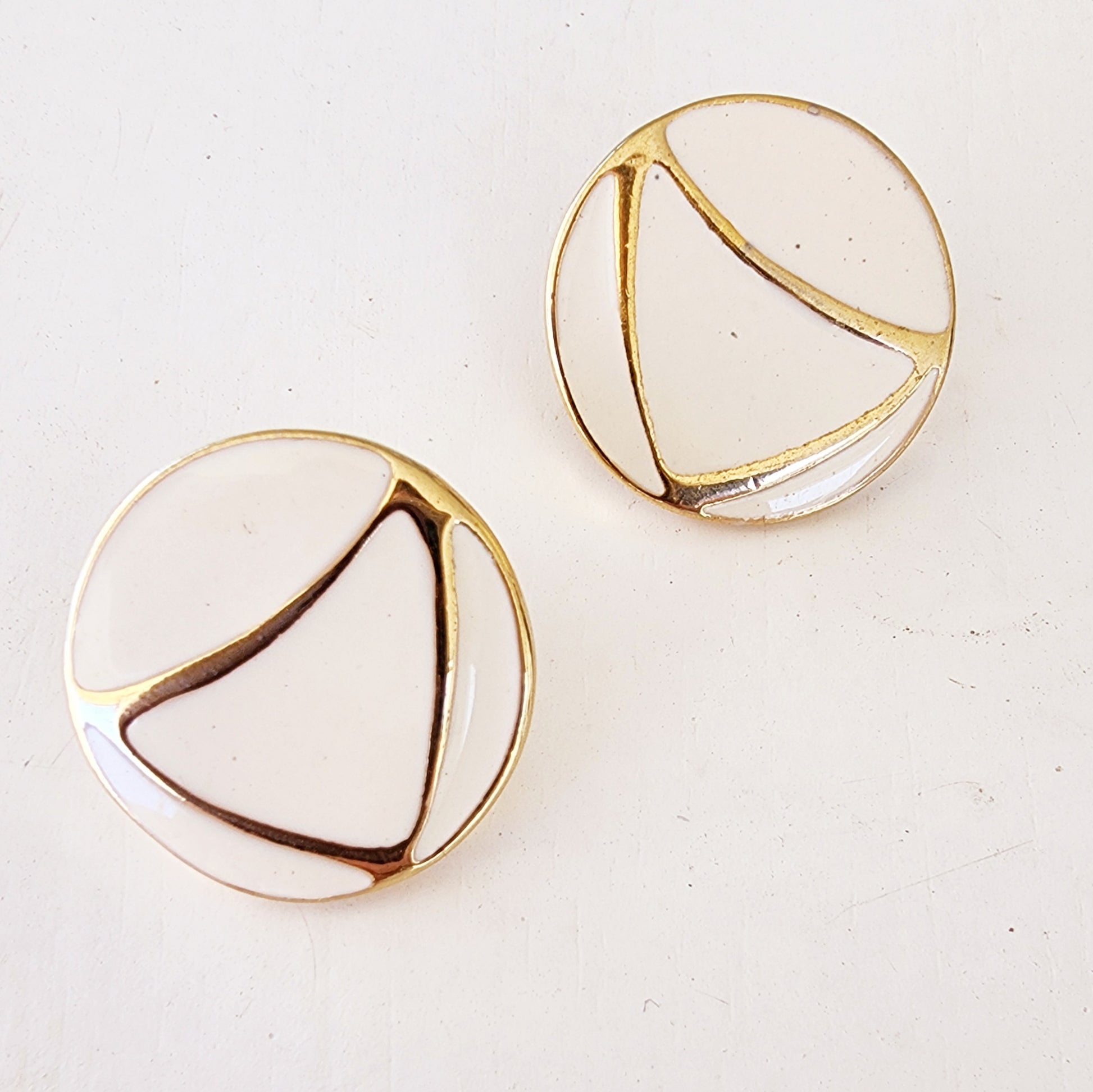 Viintage style round enamel and gold-plated earrings with off-white geometric pattern, front view on white background