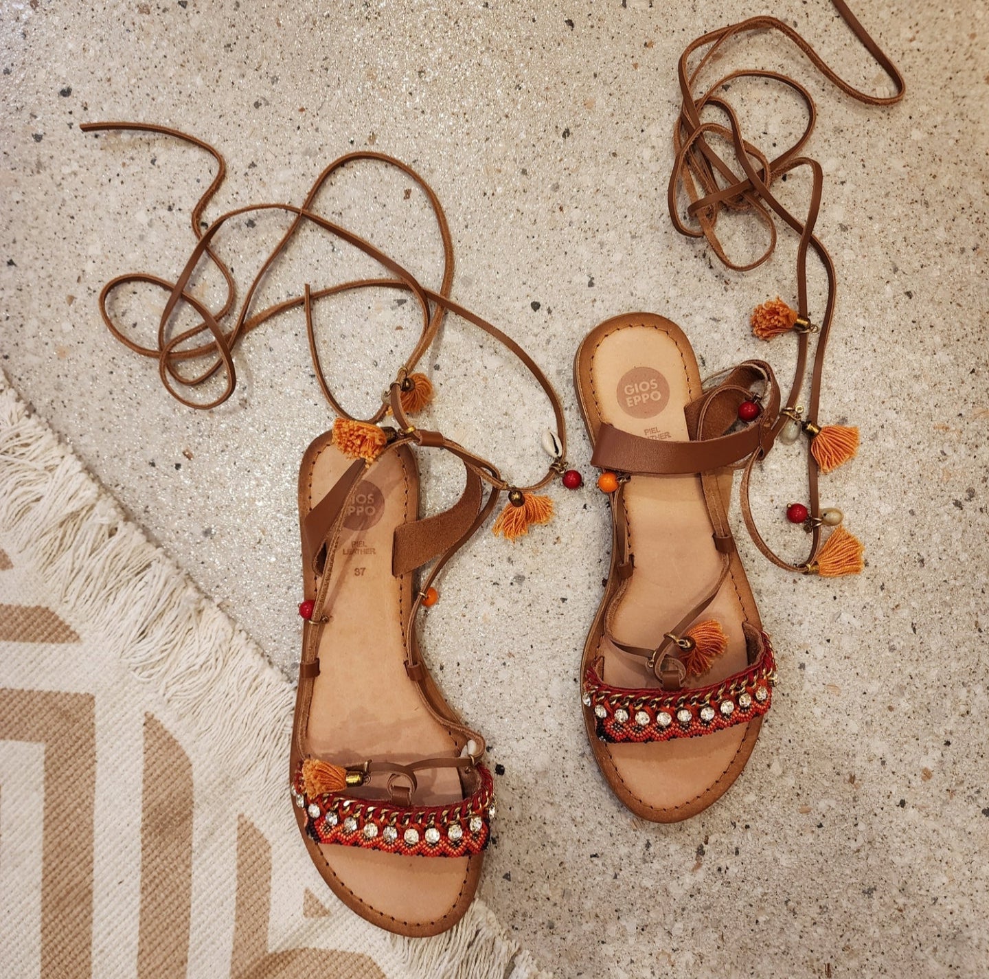 Gioseppo Ioana sandal with tan leather ties, shells, and mustard-orange tassel details, top view.