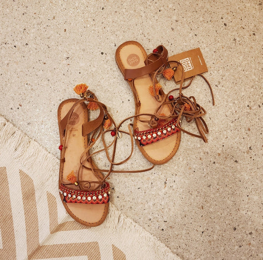 Gioseppo Ioana sandal with tan leather ties, shells, and mustard-orange tassel details, top view.