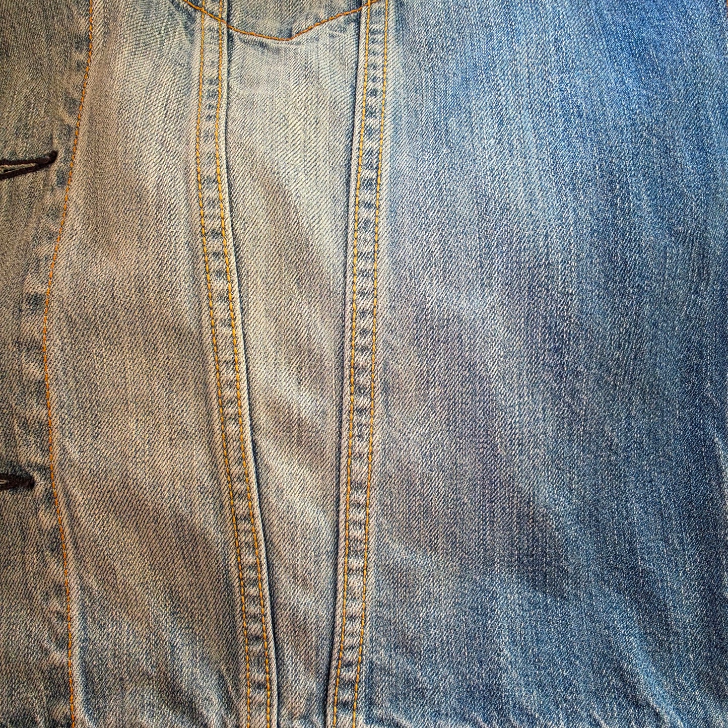 Close-up of blue denim Levis trucker jacket, showing the factory fading and contrast stitching details