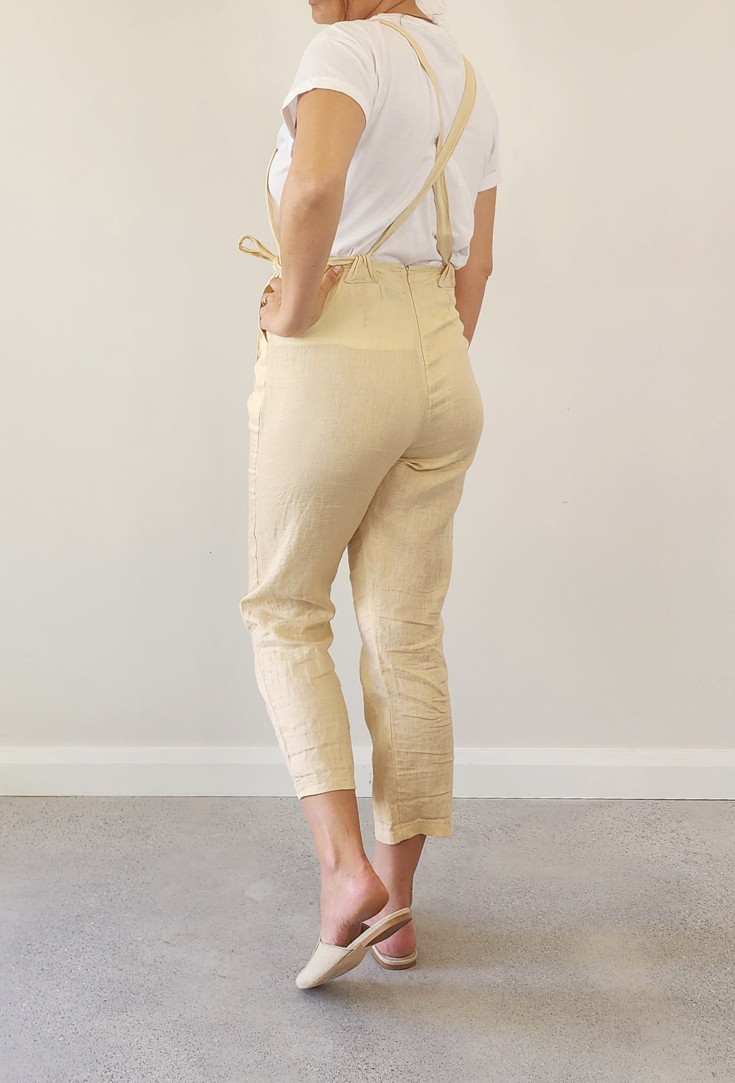Back view of Lilya oatmeal linen overalls, highlighting adjustable straps and straight-leg cut.