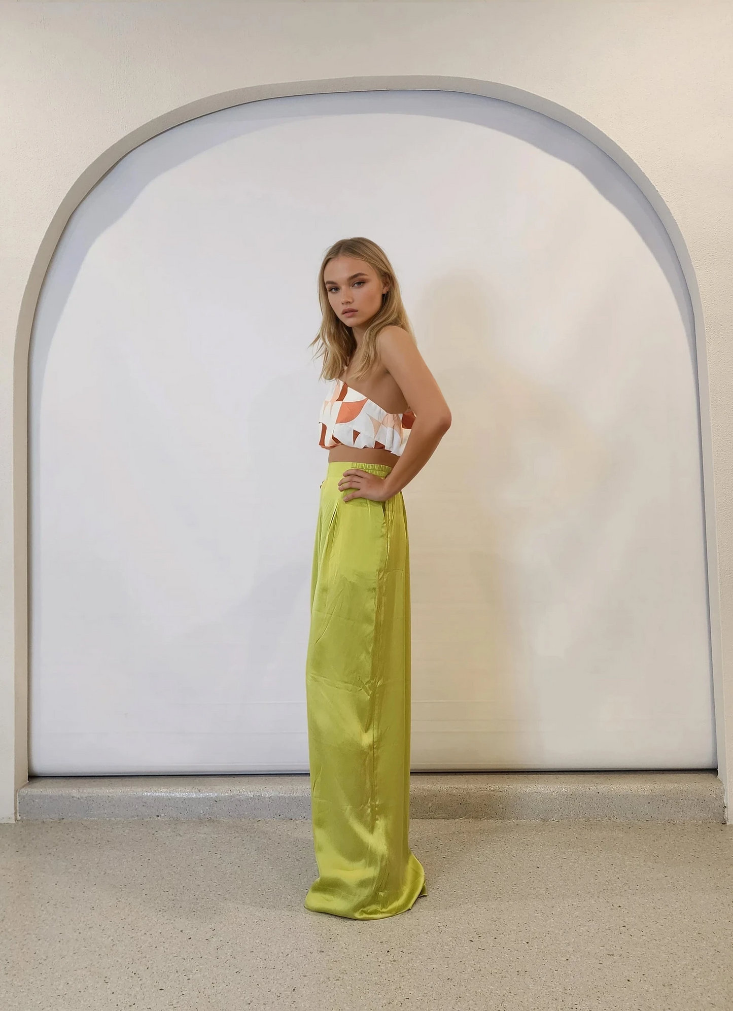 Side profile of model in high-waisted, silk wide-leg pants in a fresh green tone.