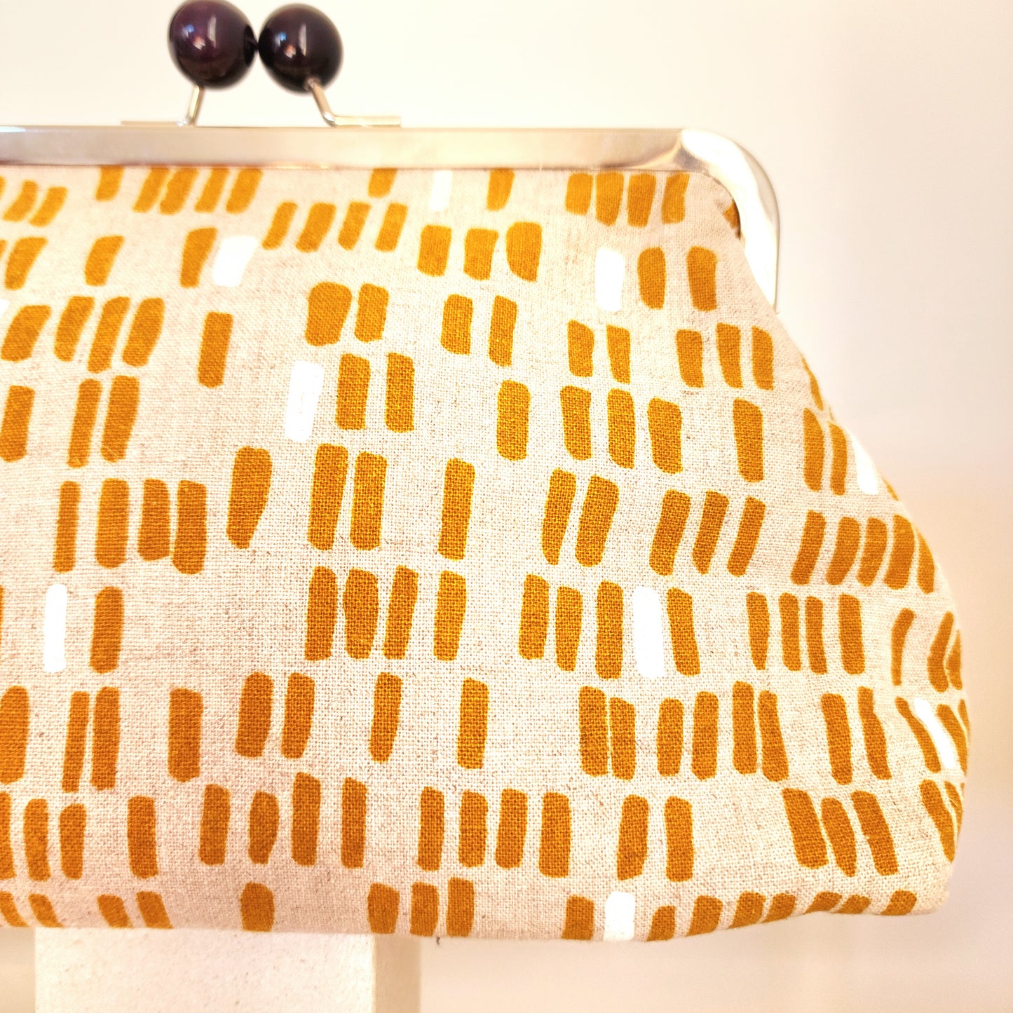 A close-up view of the retro clutch bag's line design in mustard colour.