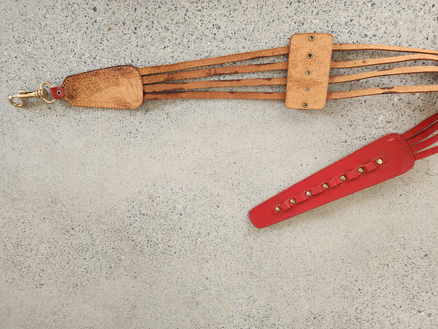 Rouge red leather multi-strap waist belt with brass studs and clip fastening, raw leather backing showing discolouration.