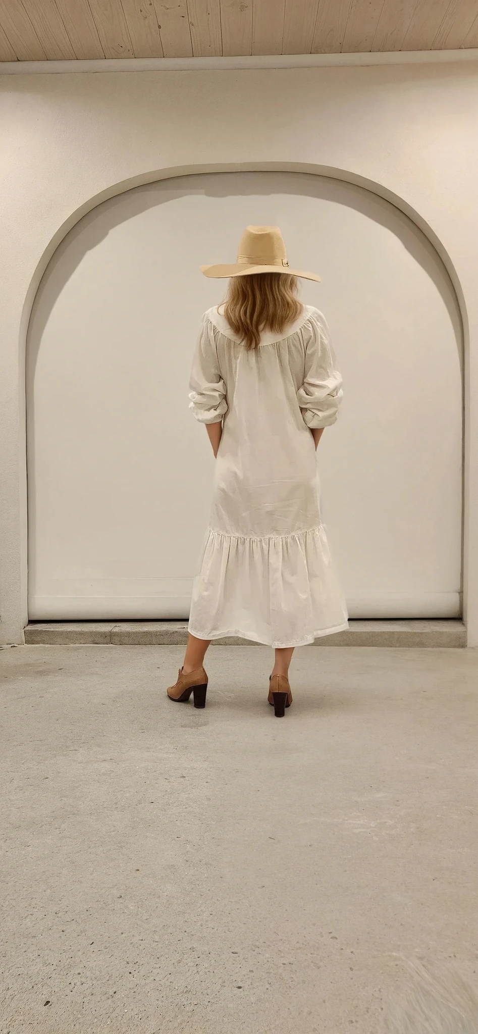 Back of long white maxi dress showing relaxed fit and curved yoke, styled with western hat