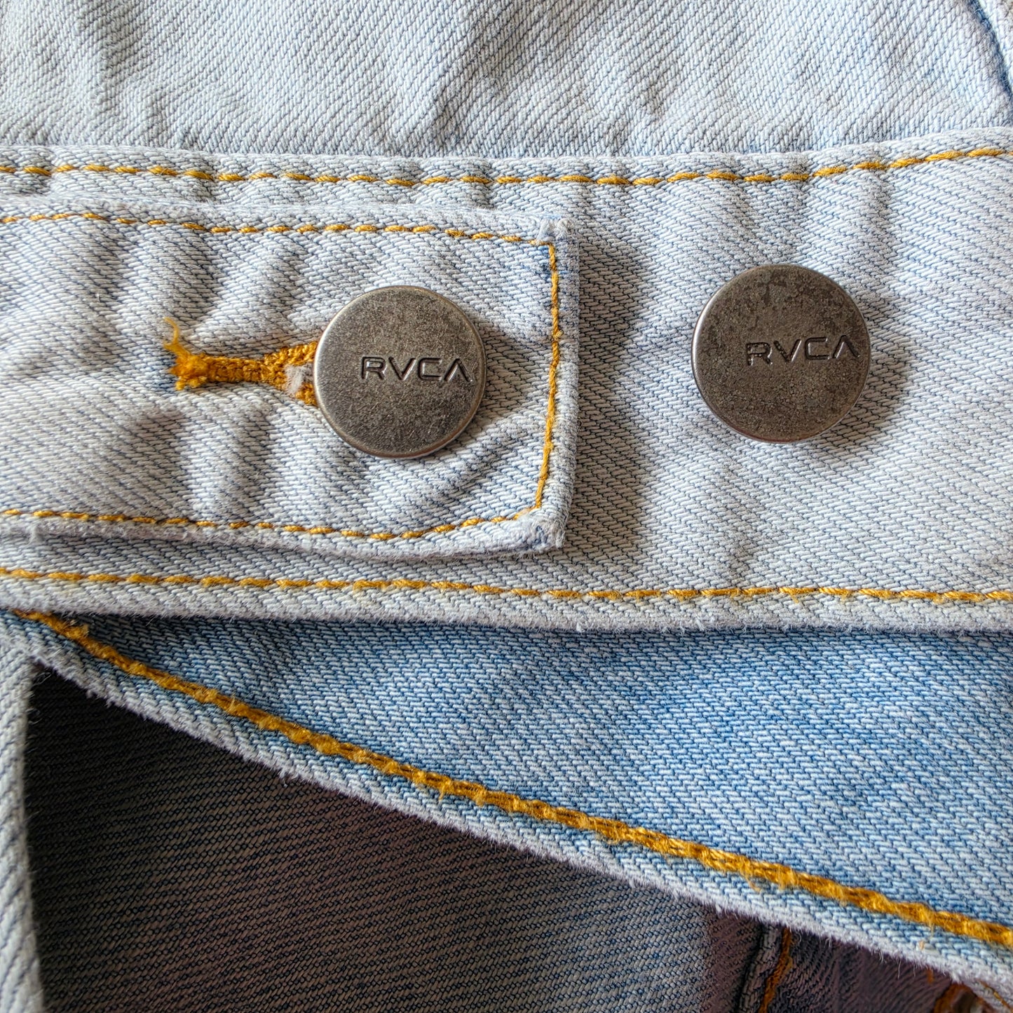 Close-up- view of the buttons on the RVCA distressed denim jacket.