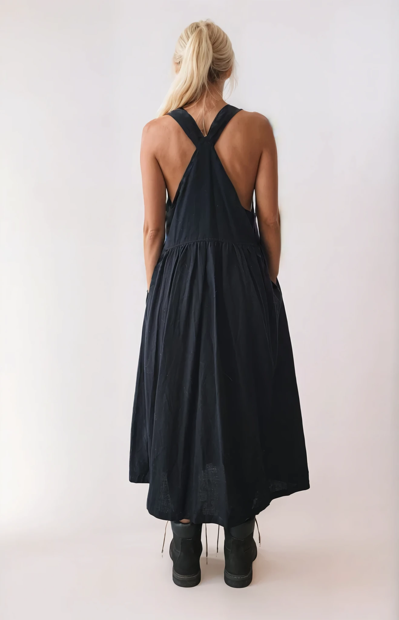 Back view of black pinafore dress with criss-cross straps and softly gathered skirt.
