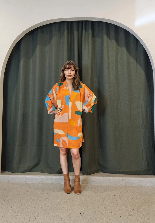 Front view of a vibrant State of Georgia dress in size L, featuring a relaxed, flowing silhouette with flutter sleeves and a vivid abstract print. The model wears it tied at the back with sleeves softly rolled.