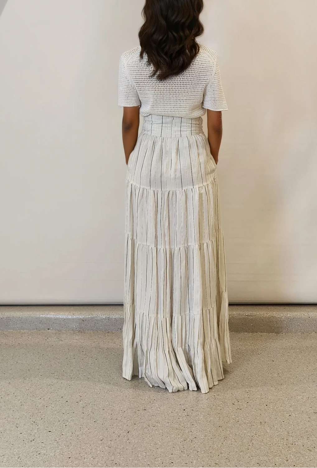 Rear view of the skirt’s flowing silhouette and fine stripe detail.