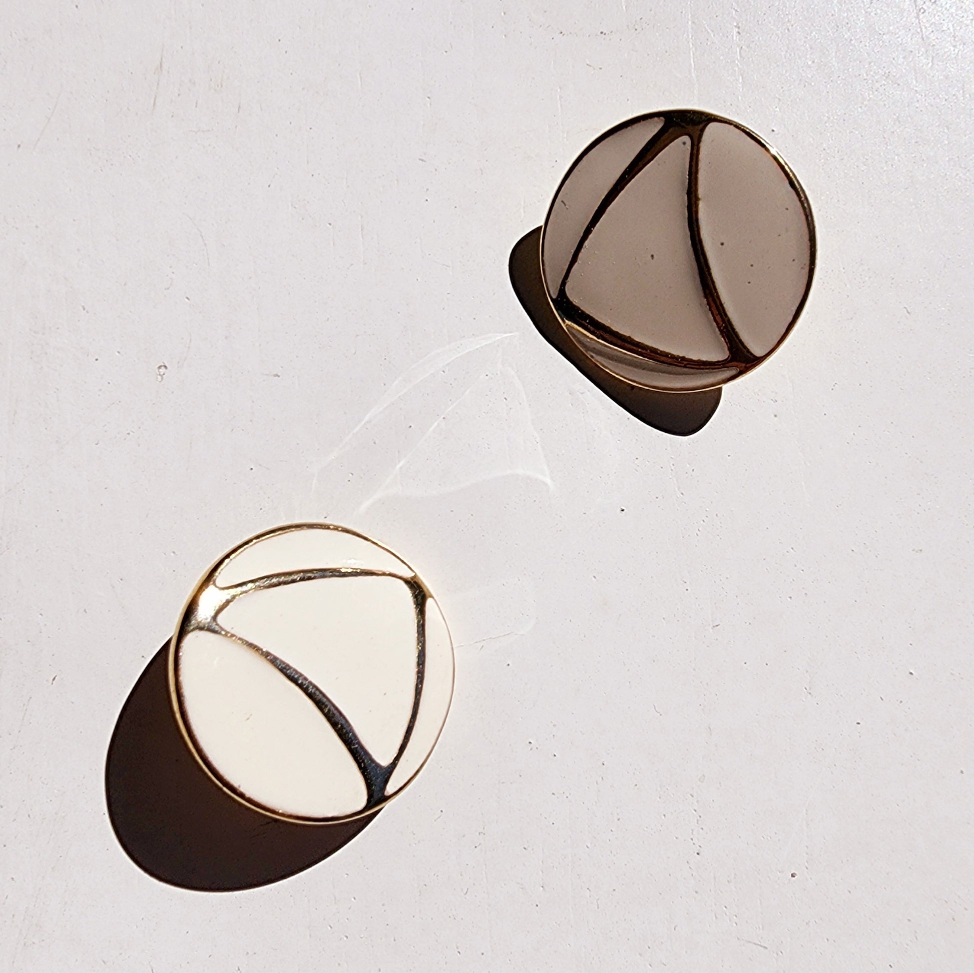Vintage style gold and off-white enamel earrings shown at an angle, highlighting shape and gloss