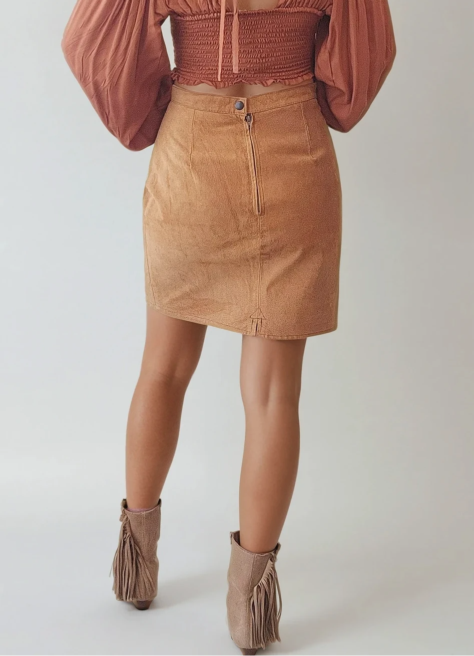 Back view of Vintage Vinetti suede skirt in tan mustard. Showing the zip and button closure and small back split. Styled on a model with fringe boots and a western hat.