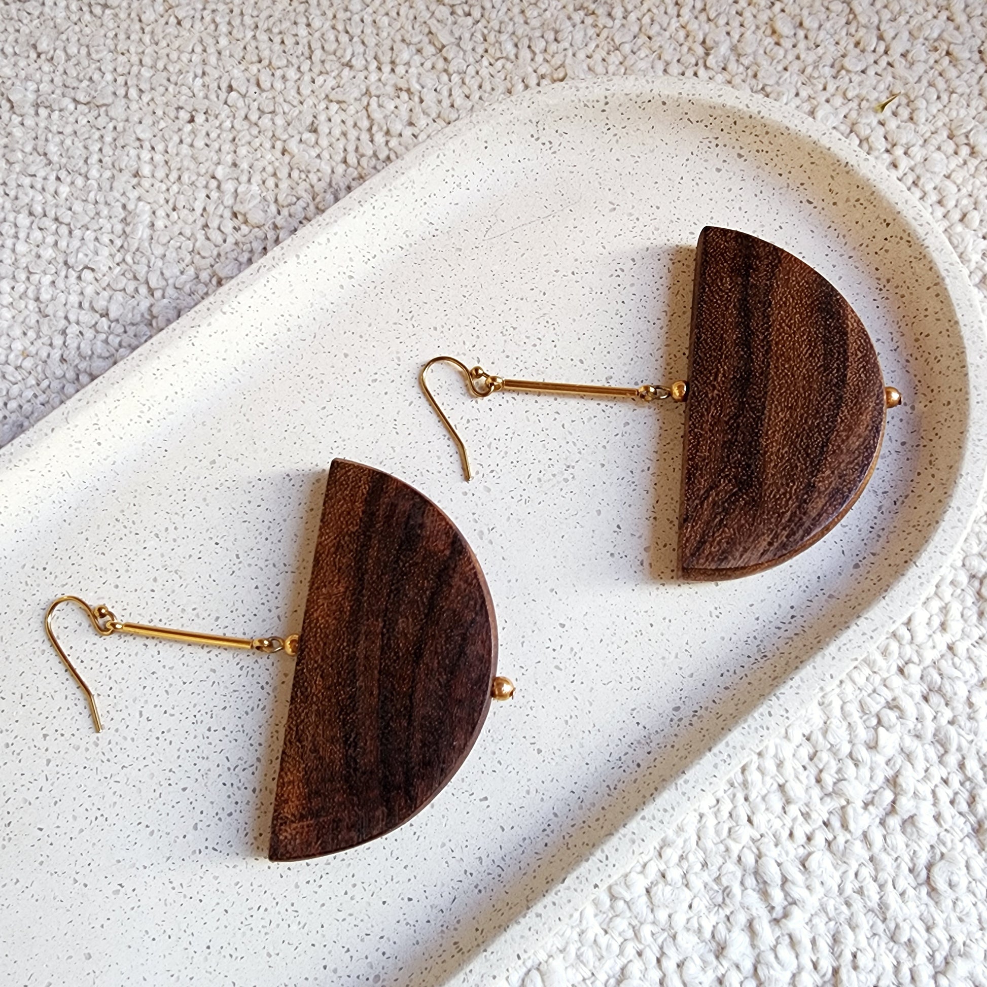 A close up view of the Cassie handmade earrings, showing the beautiful woodgrain and gold plated hardware.