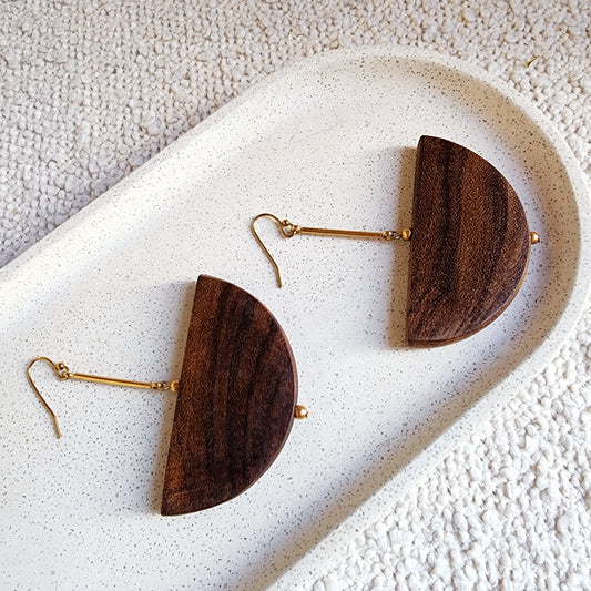 A close up view of the Cassie handmade earrings, showing the beautiful woodgrain and gold plated hardware.