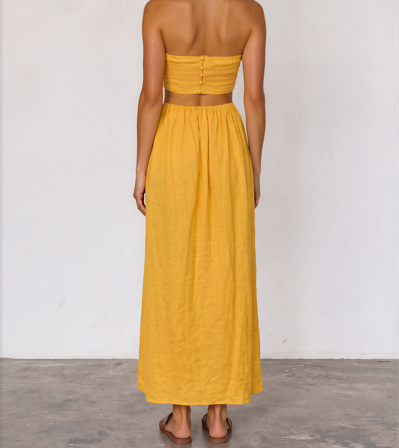 Aere marigold strapless dress with a textured bodice, side cut-outs, button up back and flowing skirt.