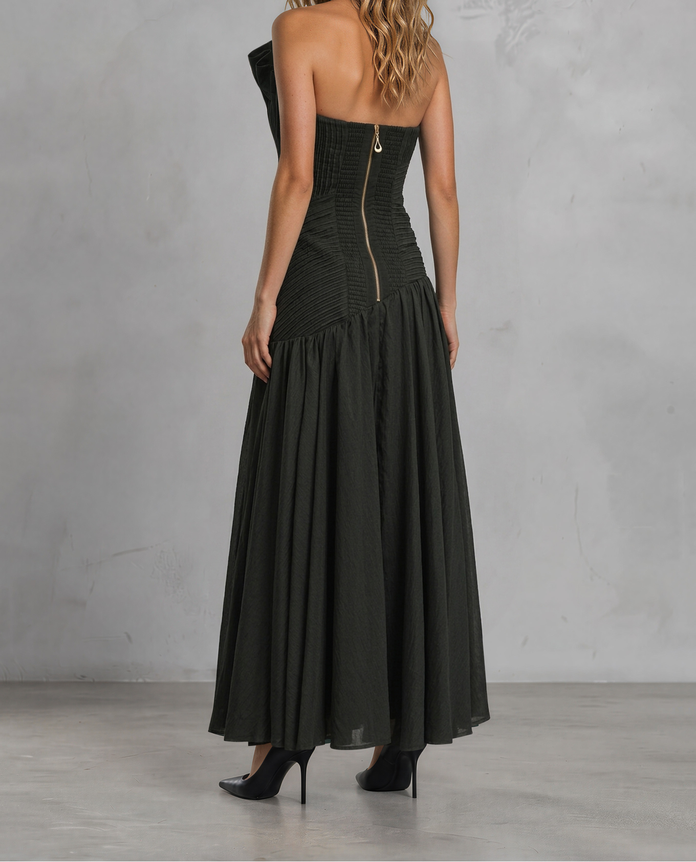 Model wearing the Aje Aquiline Gown, showing the back pleated details and gold zipper.