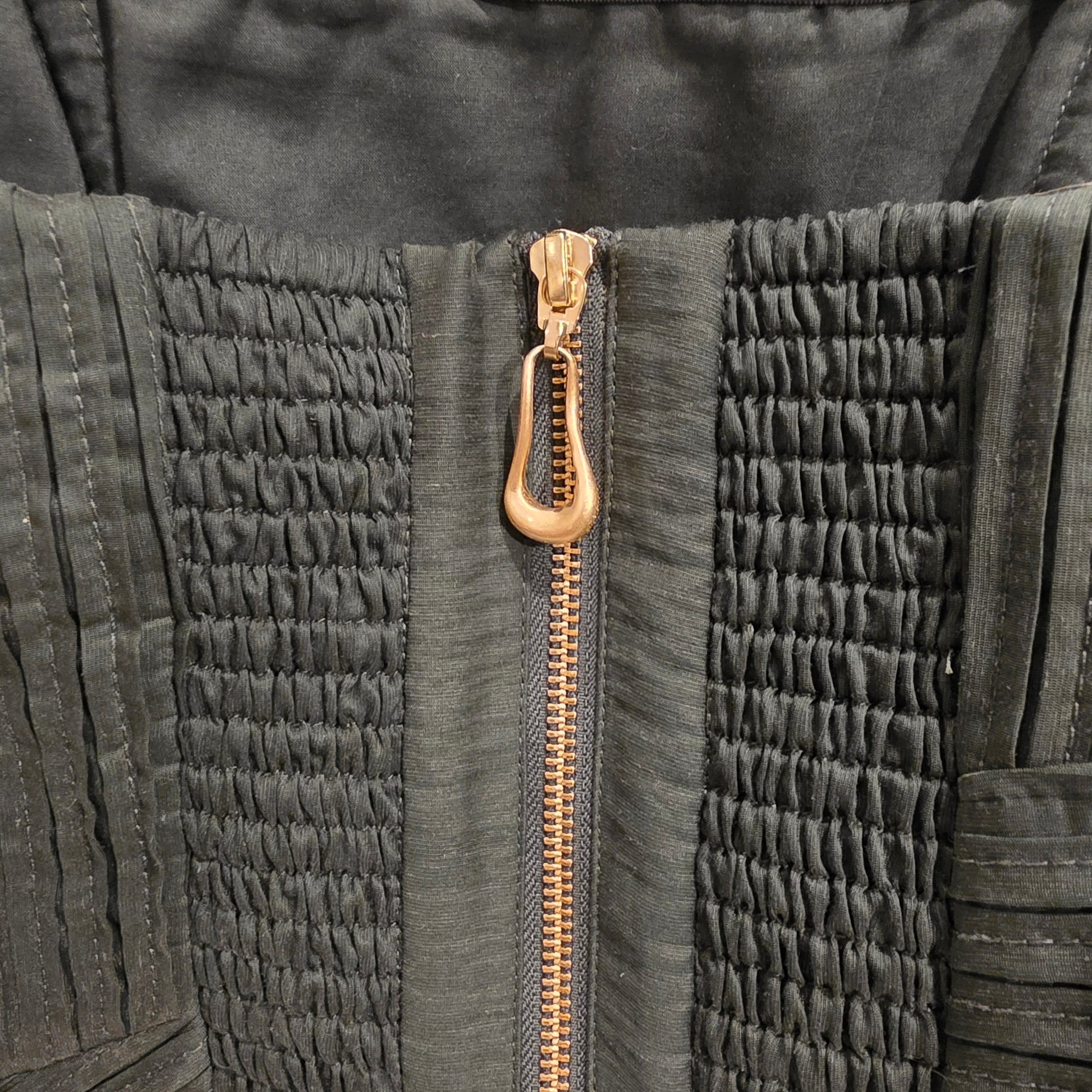 Close-up of a the textured fabric on the Aje aquiline dress showing the gold zipper detail.